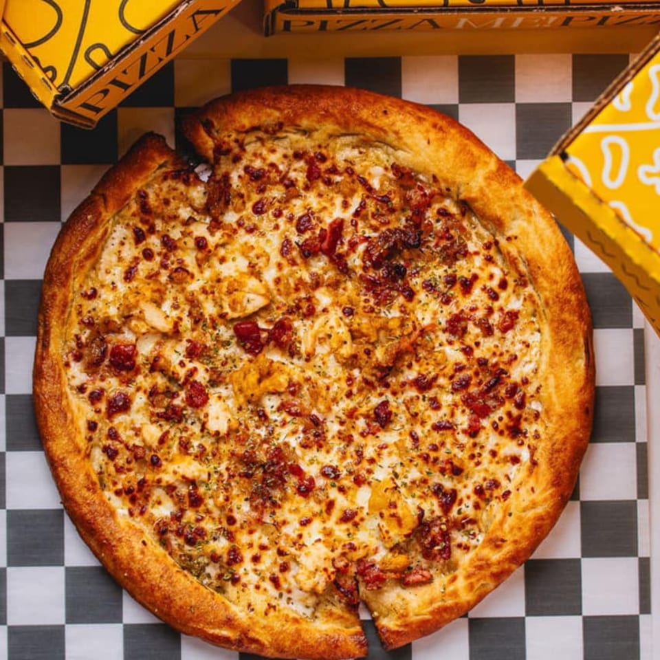 A whole PizzaMe! pizza with chicken and bacon, on a checkered paper with yellow boxes.